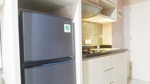 A kitchen with a double-door refrigerator, white cabinets, and a tiled backsplash. - Minimalist Studio Apartment at Supermall Mansion Orchard (Surabaya)
