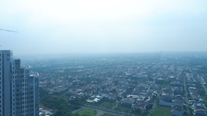 A high-rise building with a view of a residential area below. - Minimalist Studio Apartment at Supermall Mansion Orchard (Surabaya)