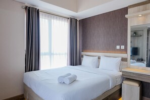 A hotel room with a large bed, a wooden headboard, a bedside table, and a mirror.