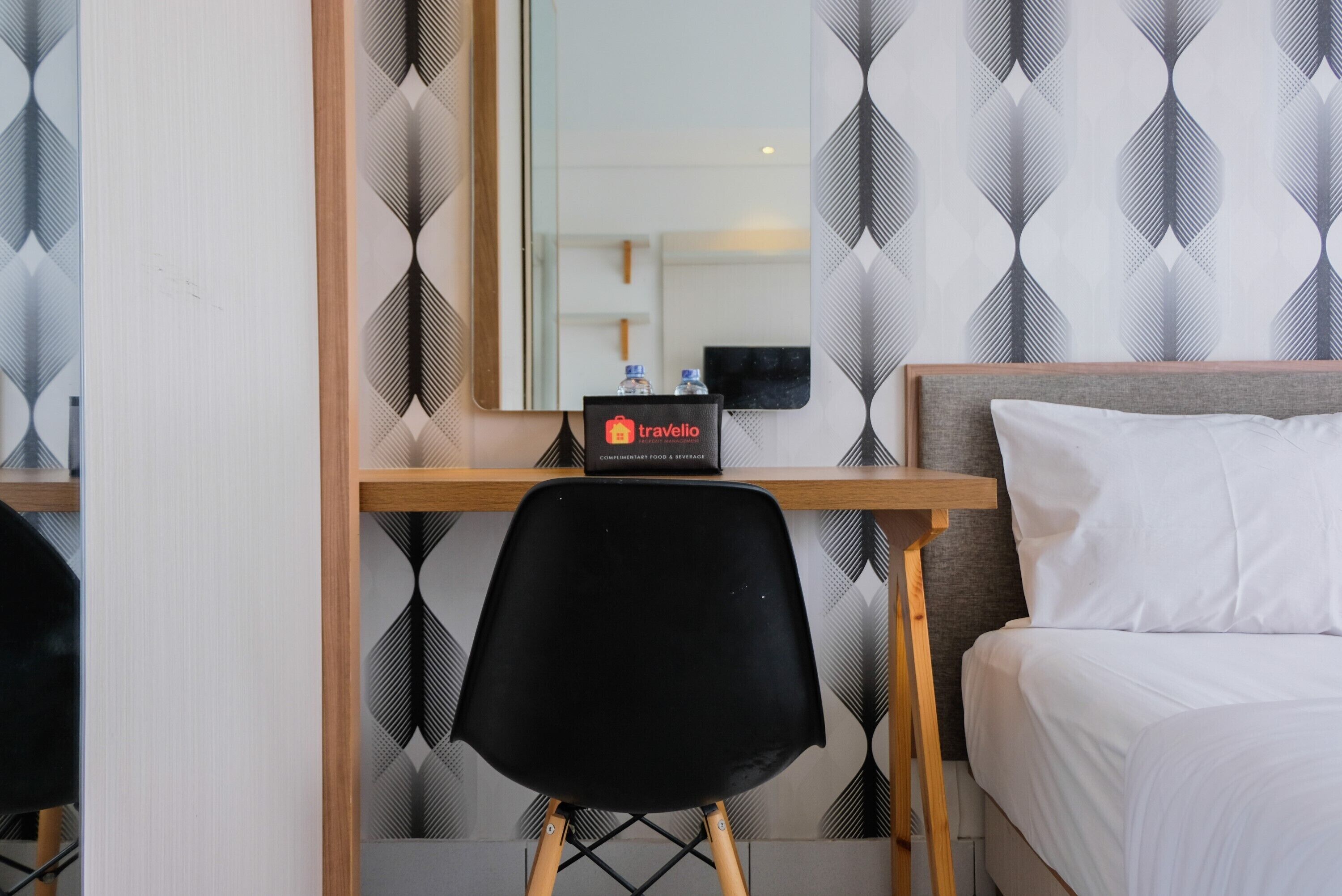 Une chambre d’hôtel comprenant un lit, un bureau avec une chaise, un minibar et un miroir.