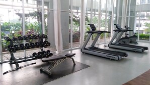 A gym with treadmills, dumbbells, and a bench.