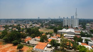 An aerial view of a cityscape with a mix of residential and commercial buildings, including a prominent high-rise tower. - Fully Furnished Studio at Serpong Greenview Apartment (South Tangerang)