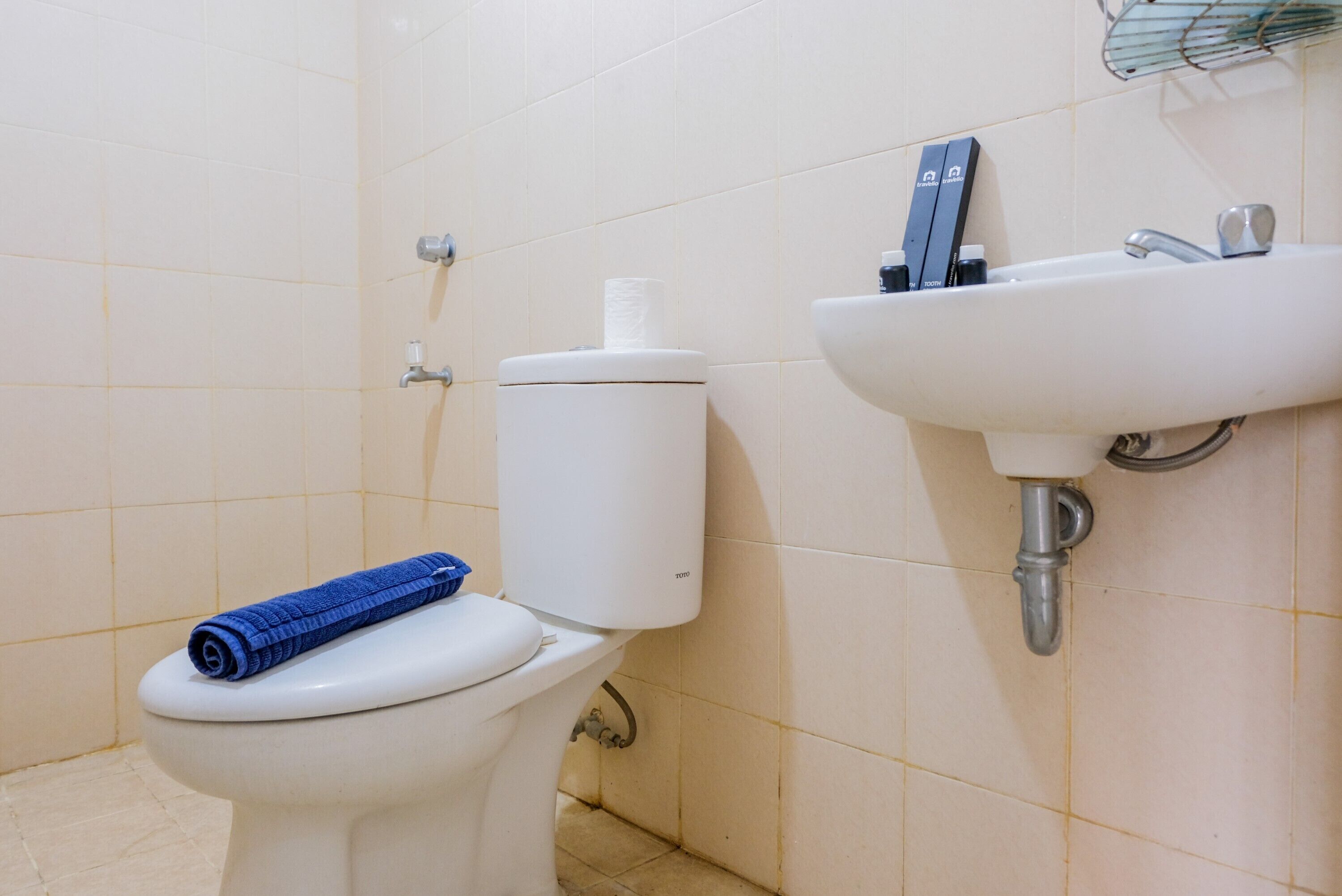 A bathroom with a toilet, a sink, and a towel on the toilet.