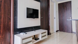 Ein modernes Wohnzimmer mit einem flachbildfernseher an einer weißen Wand, einer Holztür und einem gefliesten Boden.