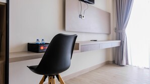 A modern hotel room with a black chair, a mounted TV, a flat-screen TV above a wooden console, and a window with curtains. - Highest Value Studio Room at Annora Living Apartment (Tangerang)