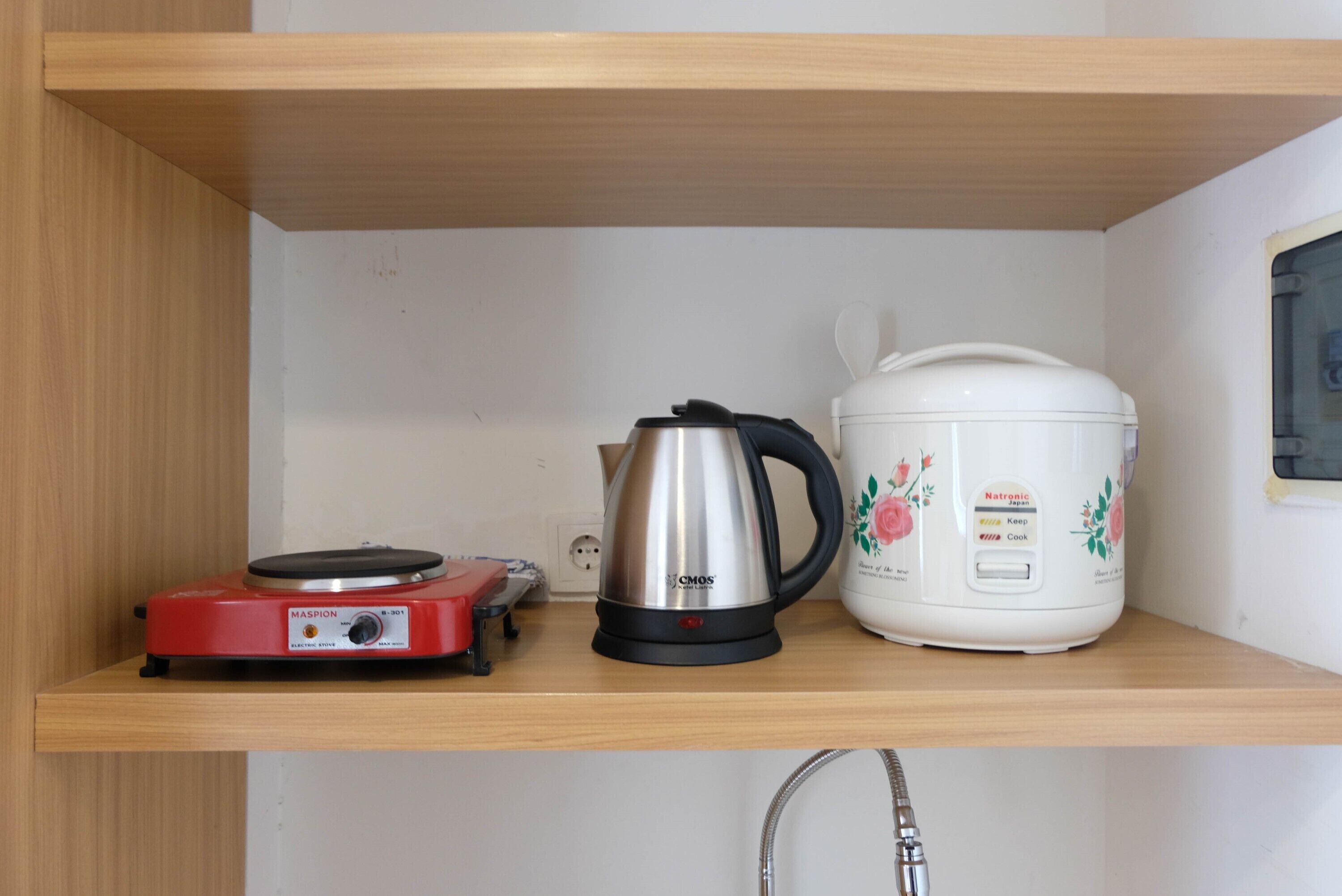 A kitchen shelf with a red electric stove, a silver pot, and a white slow cooker.