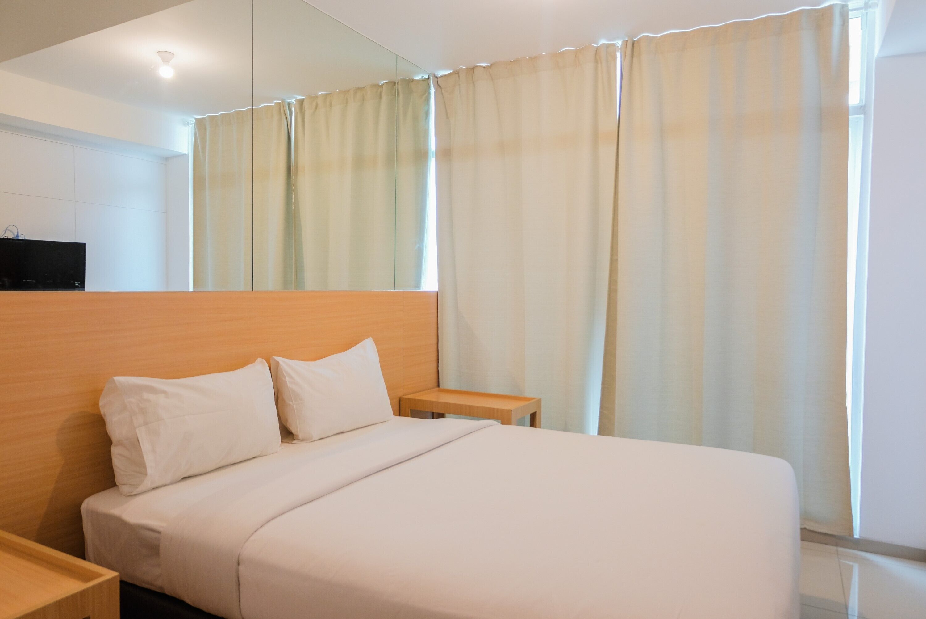 Ein Hotelzimmer mit einem großen Bett, einem Holzkopfstück, einem Nachttisch und einem Spiegel an der Wand.