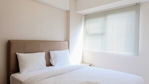Una habitación de hotel con una cama grande, cabecero y una ventana con persianas.