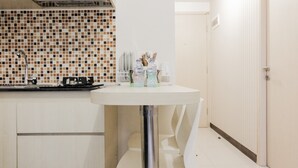 Una cocina pequeña con salpicadero de azulejos, un lavabo blanco y una mesa redonda con sillas.
