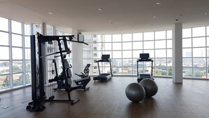 A spacious gym with large windows, exercise equipment, and a city view. - Simply and Homey Studio Apartment at Tree Park City (Tangerang)
