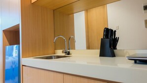 A modern kitchen with a stainless steel sink, wooden cabinets, and a black knife block. - Simply and Homey Studio Apartment at Tree Park City (Tangerang)