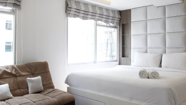 Ein Hotelzimmer mit einem großen Bett, einer Sitzecke und einem Fenster mit Vorhängen.