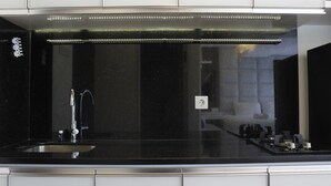 Eine moderne Küche mit schwarzem Arbeitsplatz, Edelstahlgeräten und einem eingebauten Backofen.