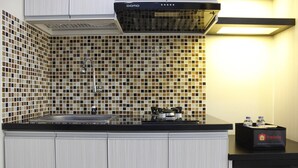Une cuisine avec un plan de travail noir, des armoires blanches et un pare-feu en carreaux.