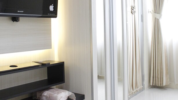 Une chambre d’hôtel moderne dotée d’un téléviseur à écran plat fixé au mur, d’une coiffeuse avec un miroir et d’un dressing avec des portes coulissantes.
