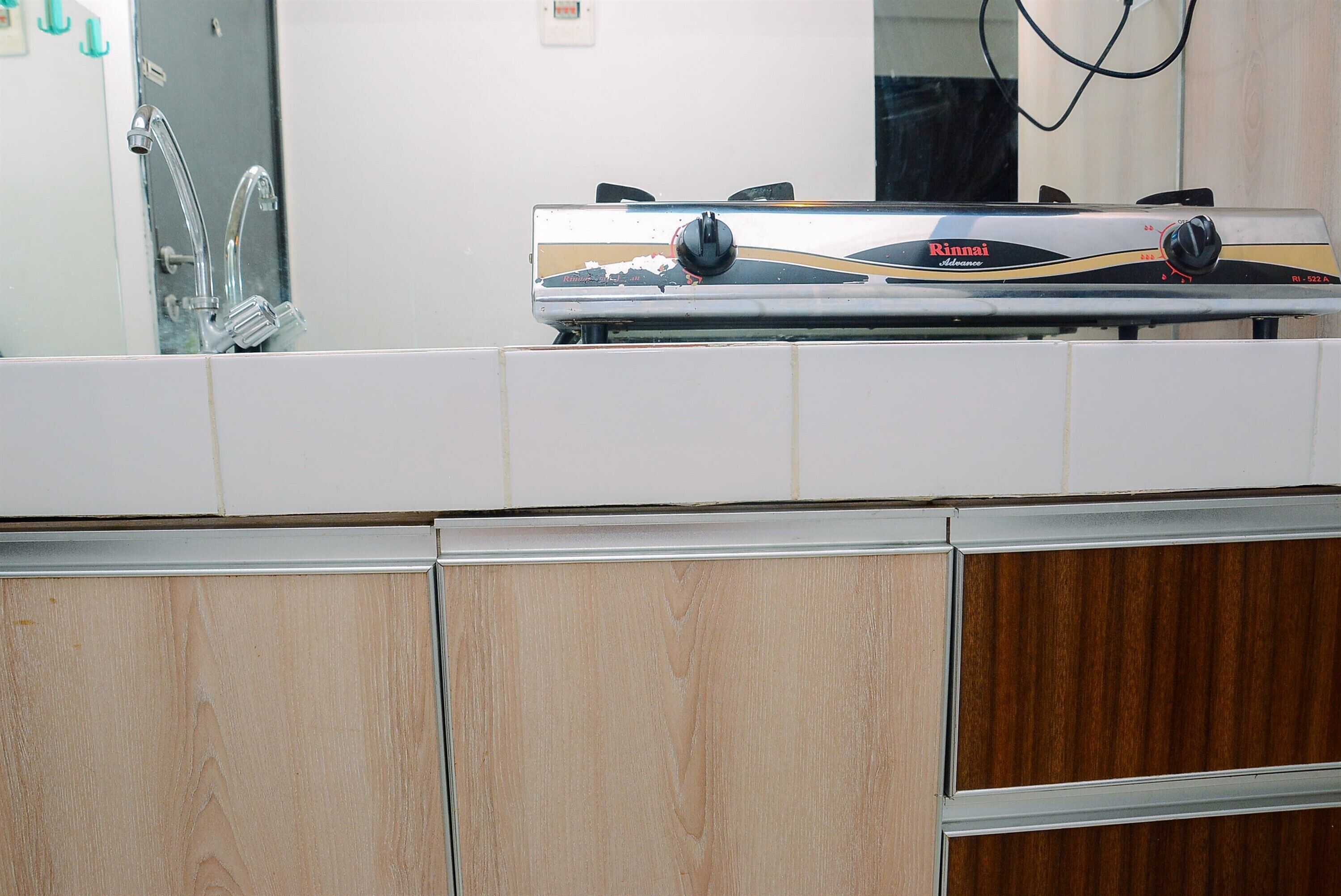 A kitchen with a Rinnai gas stove, a stainless steel faucet, and wooden cabinets.