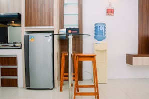 A kitchen with a refrigerator, a water dispenser, and a wooden stool. - 2BR Apartment at Park View Condominium near Universitas Indonesia (Depok)