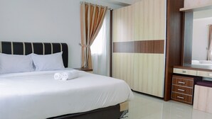 A neatly made bed with white linens and rolled towels, a wooden headboard, and a large mirror cabinet with drawers. - 2BR Apartment at Park View Condominium near Universitas Indonesia (Depok)