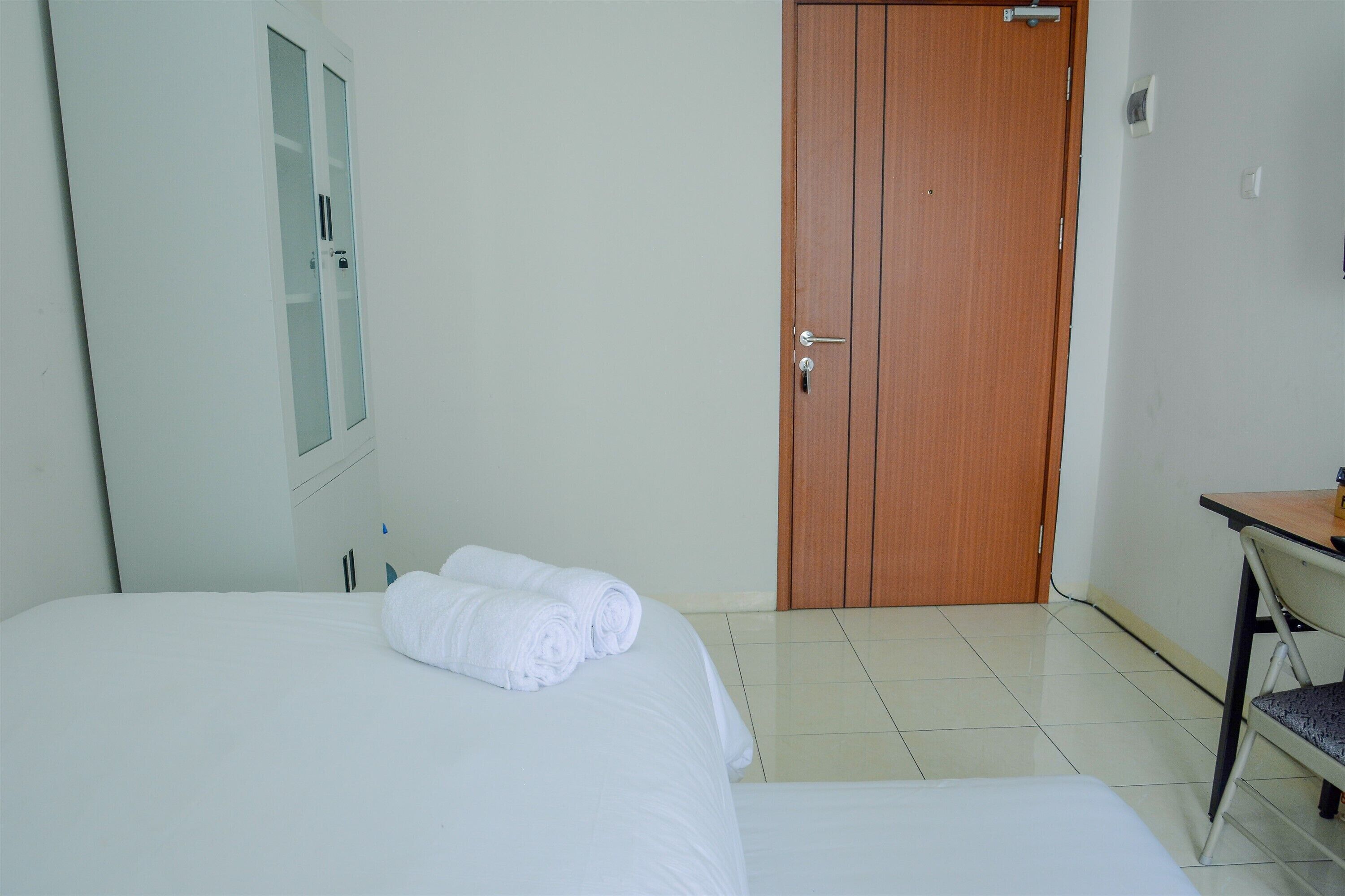 Een hotelkamer met een bed, een houten deur, een bureau en een stoel.