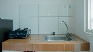 A kitchen with a gas stove, sink, and white tiled backsplash.