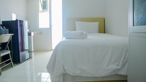 A hotel room with a bed, a chair, a desk, and a window.