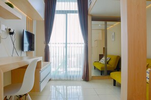 Una sala de estar moderna con un televisor de pantalla plana, un escritorio de madera, una silla blanca y un sofá amarillo.