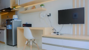 A modern kitchen with a built-in refrigerator, a coffee machine, and a flat-screen TV mounted on the wall. - Stylish and Convenient Studio Dave Apartment (Depok)