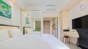Une chambre d’hôtel avec un grand lit, un bureau avec une chaise, une télévision et une salle de bain visible à travers une porte ouverte.