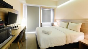 Quarto de hotel com cama, secretária e televisão, além de micro-ondas.