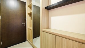 Um quarto com porta de madeira, guarda-roupa espelhado e estante de madeira.