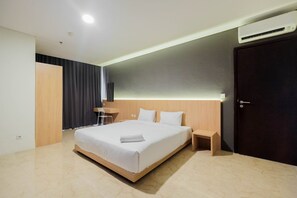 Una habitación de hotel moderna con una cama grande, mesitas de noche, un escritorio y una puerta de color oscuro.