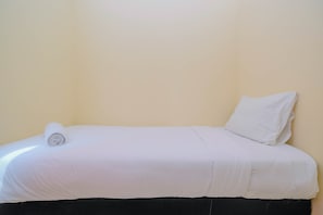 A single bed with white bedding and a rolled towel, set against a plain wall. - Big and Cozy 3BR Apartment Green Palace Kalibata (Jakarta)