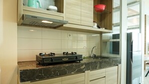 A modern kitchen with a gas stove, stainless steel appliances, and light wood cabinetry. - Cozy Studio Apartment at Nine Residence connected to Mall (Jakarta)