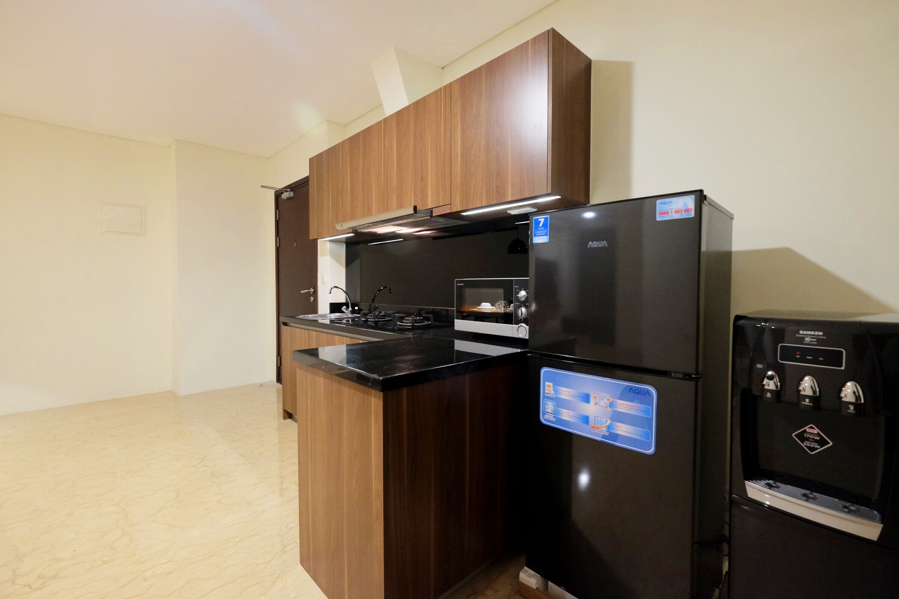 Una cocina con un refrigerador negro, horno integrado y dispensador de agua.