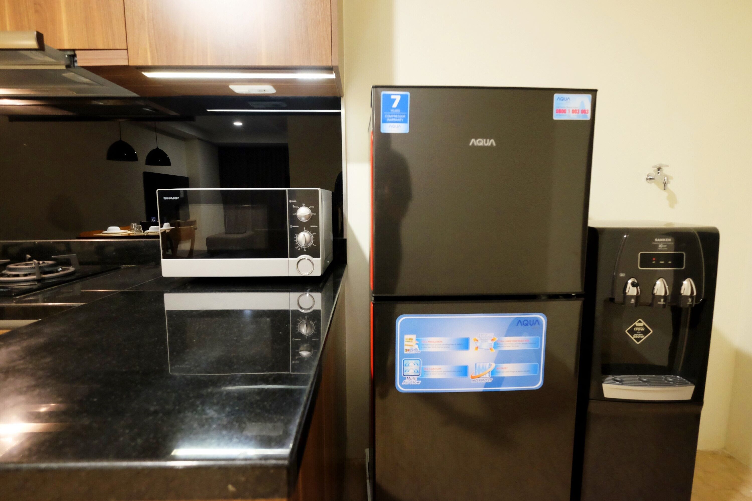 Una cucina con frigorifero nero, forno a microonde e dispenser per l'acqua.