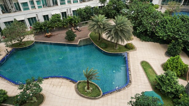 Ein großer Pool, umgeben von viel Grün und einem mehrstöckigen Gebäude.
