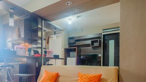 A modern living room with a sofa, a coffee table, and a kitchen area in the background. - Strategic 2BR at Kalibata City Apartment (Jakarta)