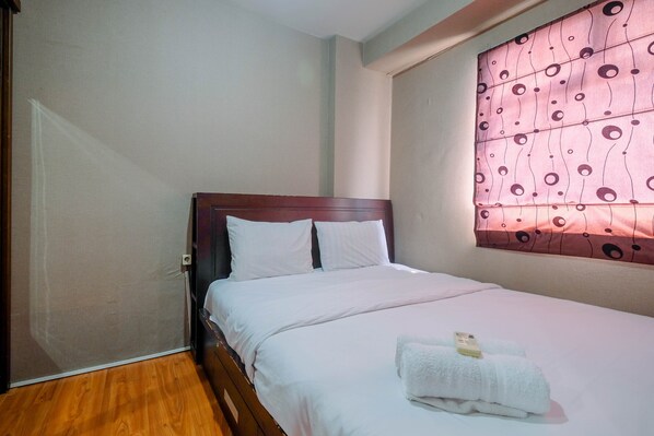 A neatly made bed with white linens and a folded towel on the bed.