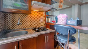 A kitchen with a gas stove, sink, and a coffee machine. - Strategic 2BR at Kalibata City Apartment (Jakarta)
