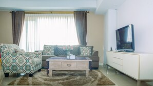 Un salon comprenant un canapé, une table basse, un téléviseur posé sur un meuble et une armoire.