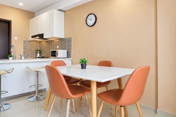 Una cocina moderna con encimera blanca, microondas y un reloj en la pared.