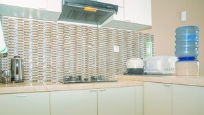 Une cuisine avec un dosseret carrelé, un distributeur d’eau, une machine à café et un four à micro-ondes.