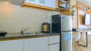 Una cocina con un refrigerador de acero inoxidable, una cafetera y un lavamanos.