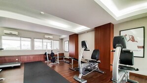 A gym with exercise equipment, wooden floors, and large windows. - Tranquil 2BR Apartment at Bintaro Park View (Jakarta)