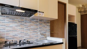 A kitchen with a black stove, a sink, and a black refrigerator. - Tranquil 2BR Apartment at Bintaro Park View (Jakarta)