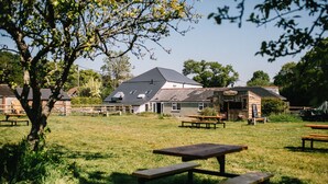 Un área verde con mesas de picnic y un edificio de techo inclinado.