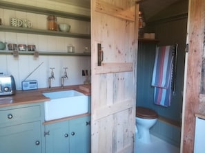 Un baño rústico con una puerta de madera, un lavabo blanco y un inodoro.