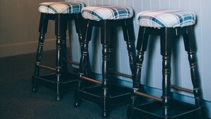 Una zona de bar con tres taburetes de madera, un mostrador de madera y una lámpara colgante.