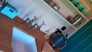 Una cocina con estantes que contienen diferentes utensilios, una cafetera y un estuche azul.