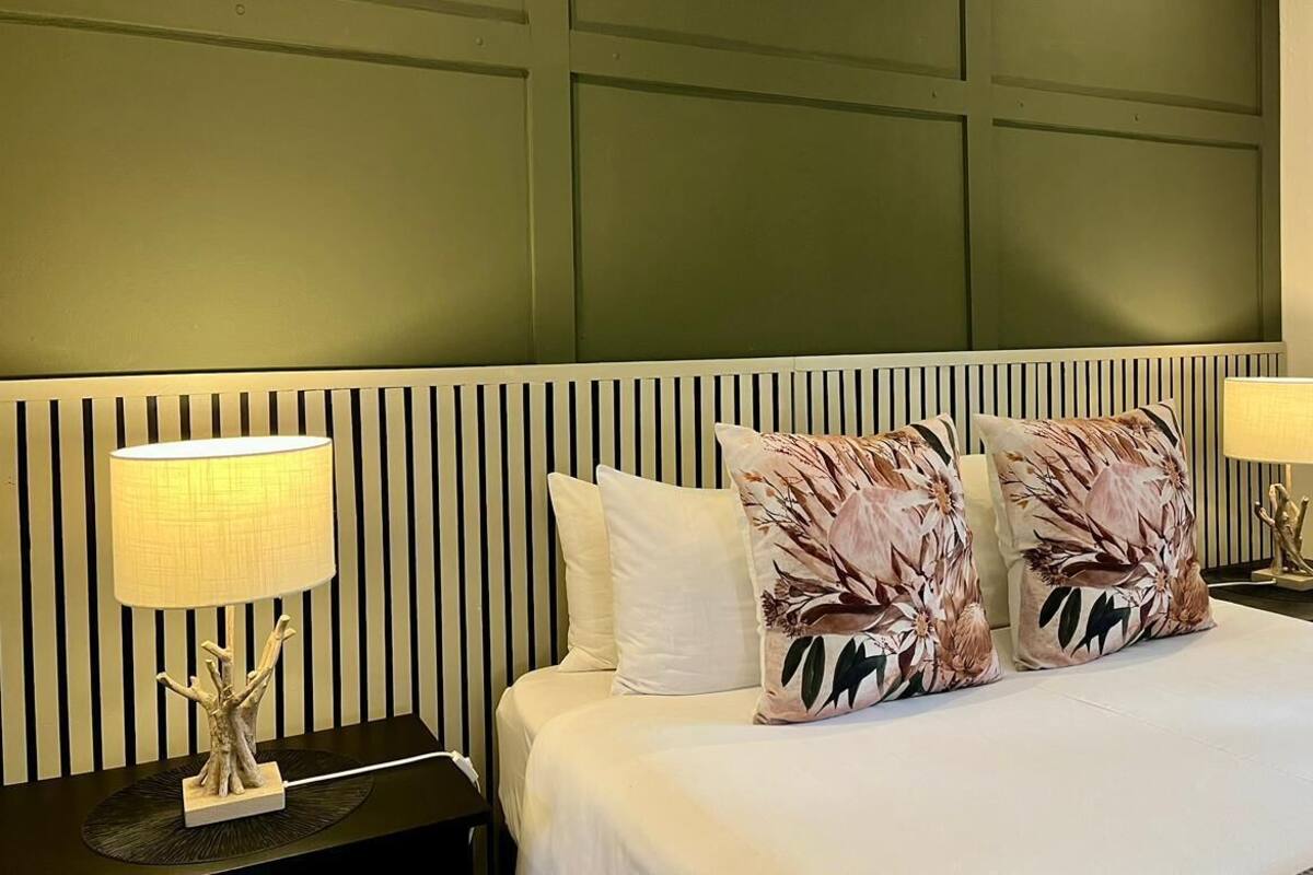 A hotel room with a bed, two nightstands, and two lamps.